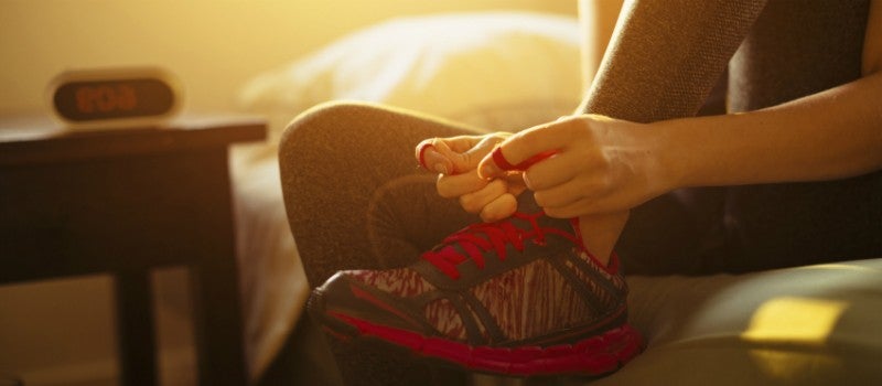A person tying up their shoe laces in preparation to go for a run. 