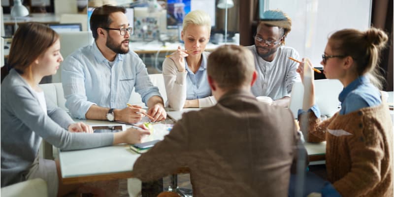 A project management team formulating a timeline and project plan around a table. 