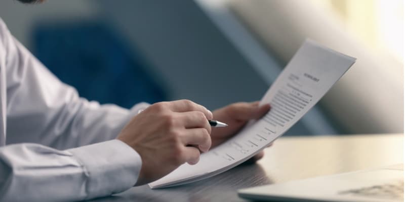 A closeup of a lawyers reading a legal document and making notes with a pen. 