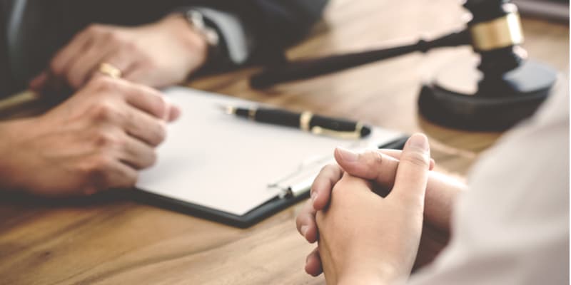 Two legal professionals discussing a legal document at a desk.