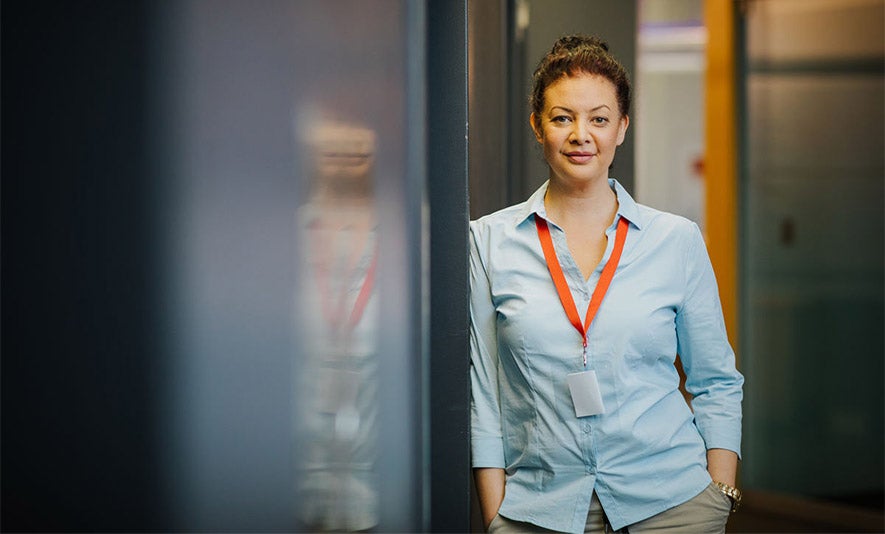 Southern Cross University Online student in a uniform leaning against the wall and smiling.