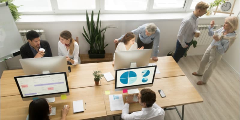 A small group of colleagues in a startup office sat at their desks discussing a project. 