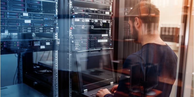 An IT technician working on the network server using his laptop.