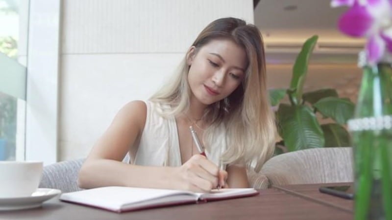 A person sitting at a desk with a planner and pen prioritises tasks.