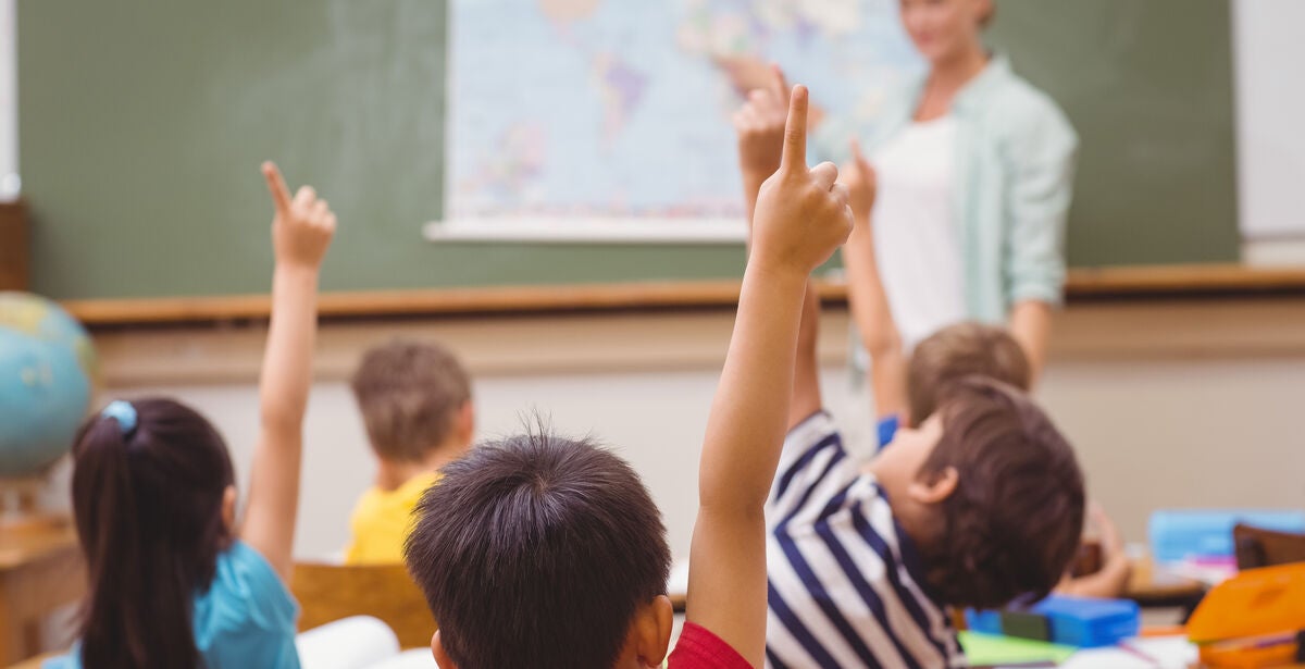 Woman teacher standing in front of classroom of kids