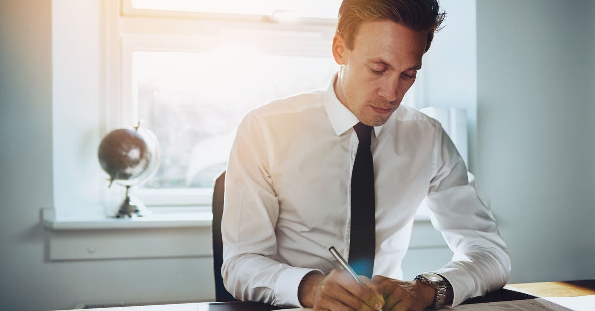 Corporate lawyer writing on paper in his office