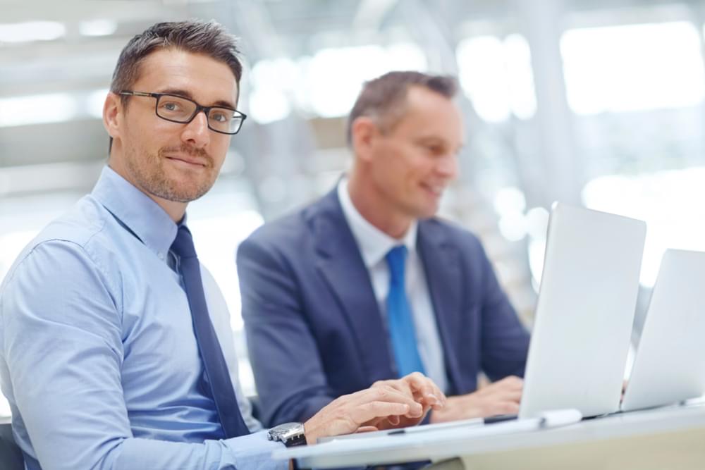 Male sitting next to a colleague wondering if he should get an MBA