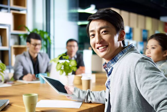 young confident asian businessman turning to look at camera during a networking event for MBA graduates