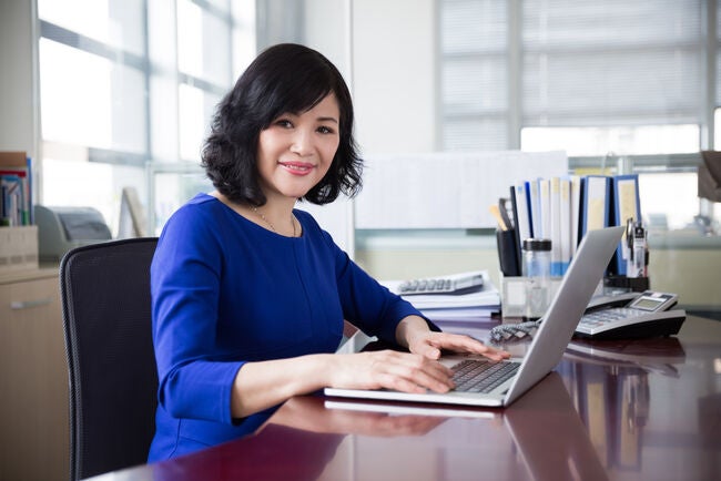 mature, middle-aged woman smiling at the camera studying her MBA
