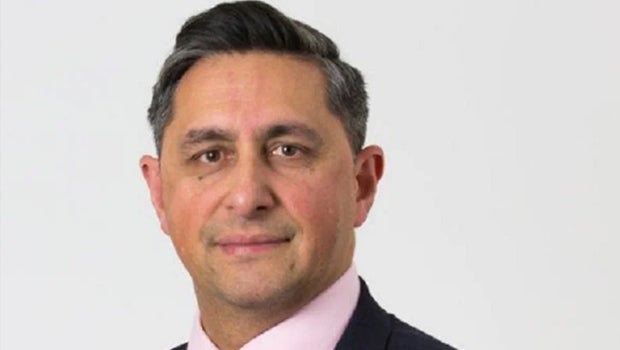 A man dressed in a formal suit and tie, featuring a distinctive pink tie, exuding professionalism and style.