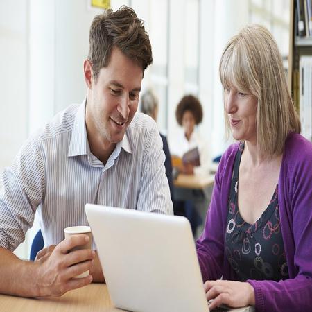 A man and female Education student sit together at a table, working on a laptop, illustrating a productive partnership