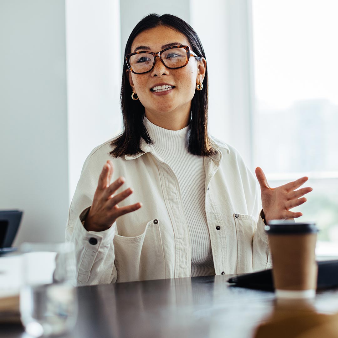 A female Master of Education student wearing glasses engages in conversation with another person, showcasing an attentive and interactive dialogue