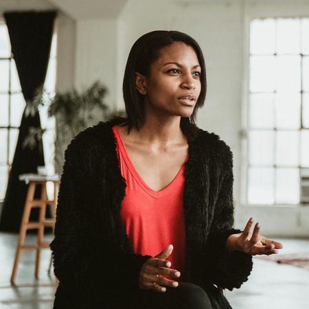 A female mental health student seated in a chair, extending her hand outward in conversation