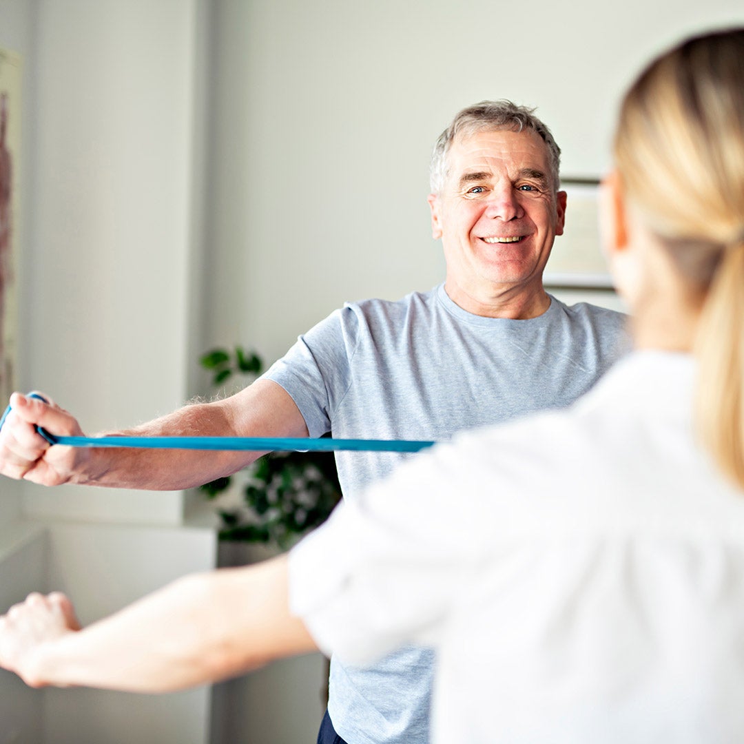 A man performs exercises in the foreground, while another man is visible in the background, observing the activity.