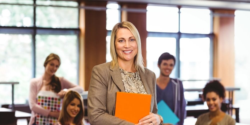 A smiling school principal surrounded by smiling teachers.