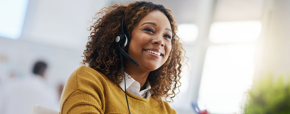 A woman with a headset, smiling warmly, exuding a sense of professionalism and approachability.