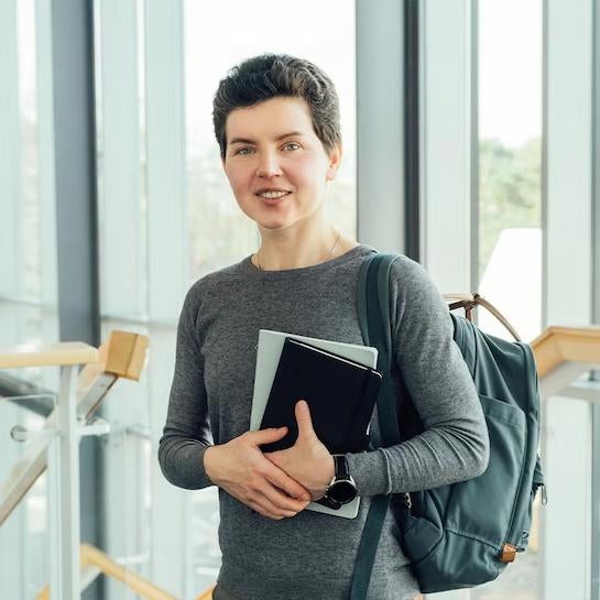 Master of Education student holding books smiling at camera