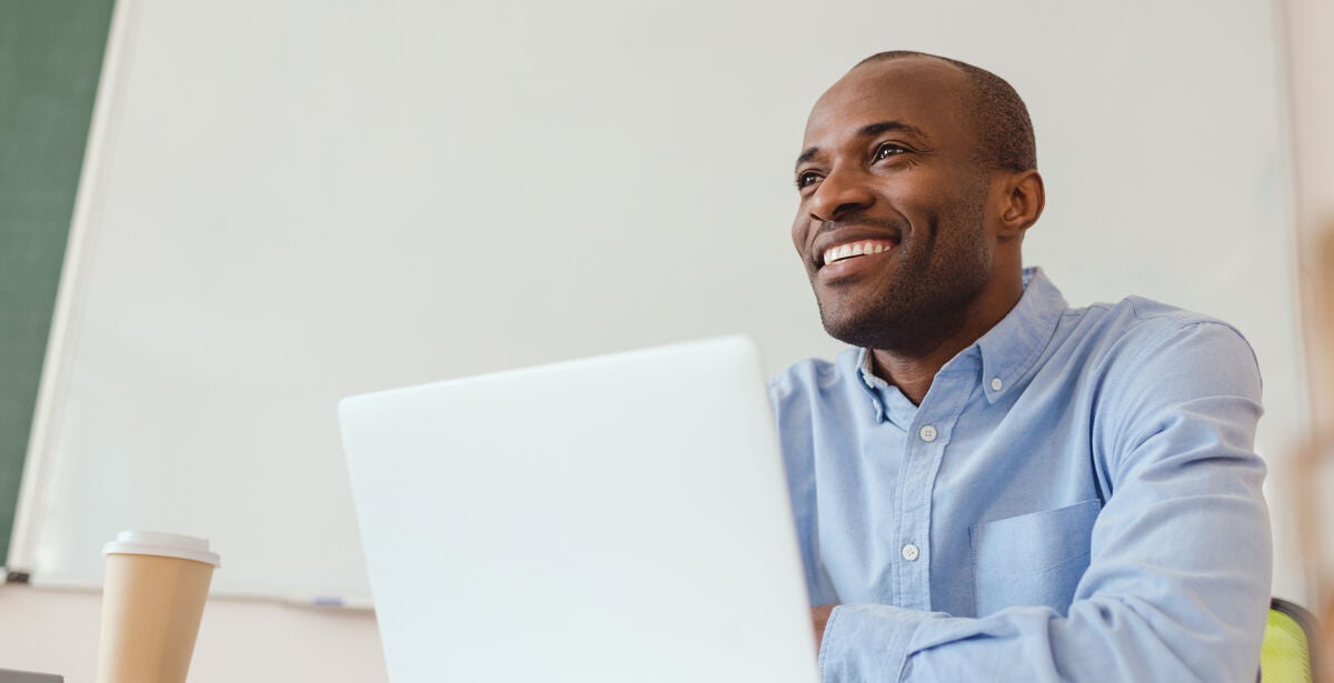 Man smiling looking ahead while on his laptop