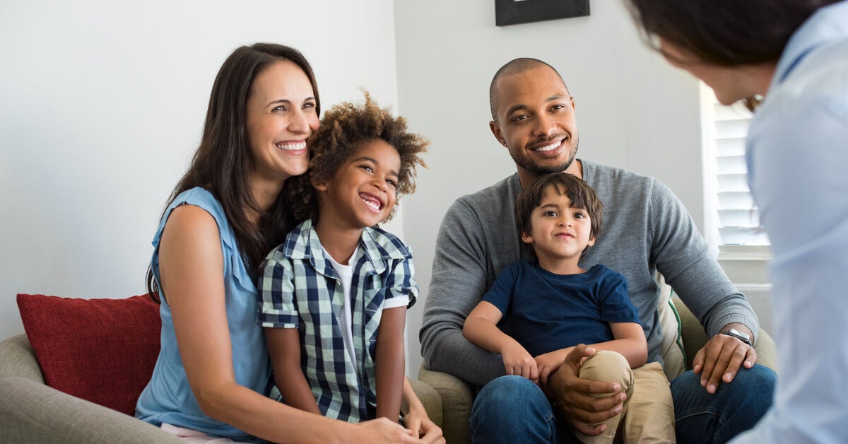 Happy young family sitting on couch and talking with a child protection officer.