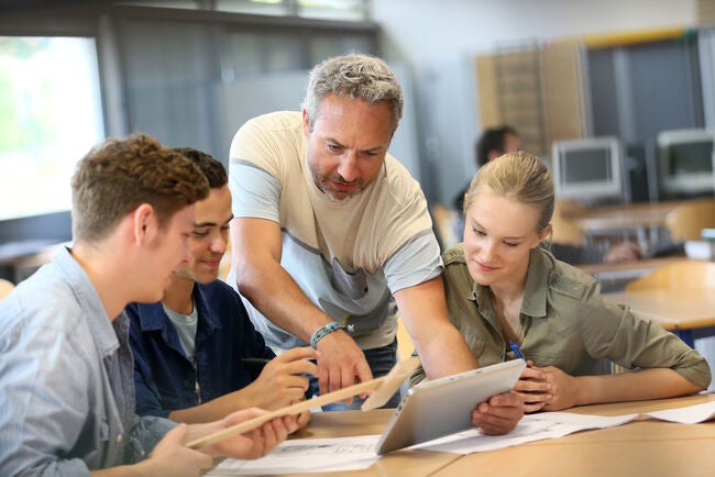 Teacher showing students digital learning on a tablet