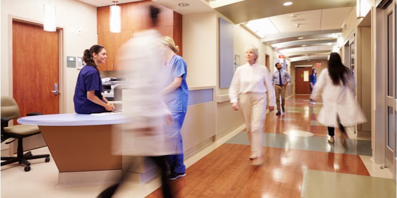 A busy hospital corridor with medical professionals and patients walking through.