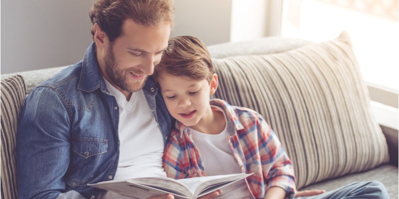 A father helping his son with his reading homework. 