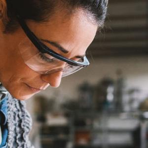 A woman focused on her project, surrounded by tools and materials in a well-organized workshop environment.