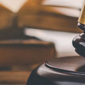 A gavel rests beside a house model on a table, symbolising the intersection of law and real estate.