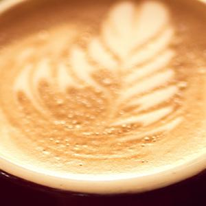 A woman's hands gently cradle a steaming cup of coffee, showcasing warmth and comfort in a cozy setting.