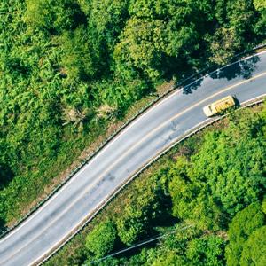 Aerial view showcasing a winding road surrounded by lush green forest, highlighting the beauty of nature and tranquility.