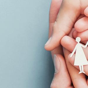 A person's hands hold a paper cutout of a family, symbolizing unity and togetherness in a heartfelt display.