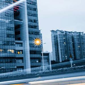 A bustling city street lined with tall buildings and parked cars, showcasing urban life and architecture.