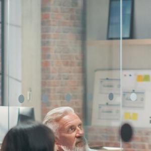 A diverse group of professionals collaborates in an office, surrounded by colorful sticky notes on the wall.