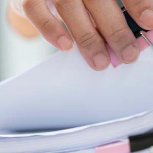 A person holds a neatly organized stack of papers secured with a clip, showcasing a professional and tidy appearance.