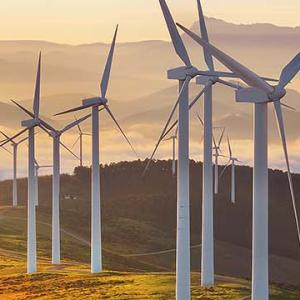 Wind turbines atop a mountain, surrounded by clouds, showcasing renewable energy in a scenic landscape.