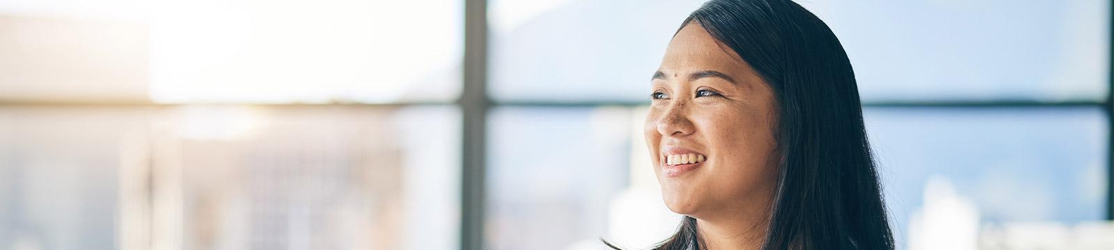 A woman smiles brightly while gazing up at the camera, exuding warmth and positivity in her expression.