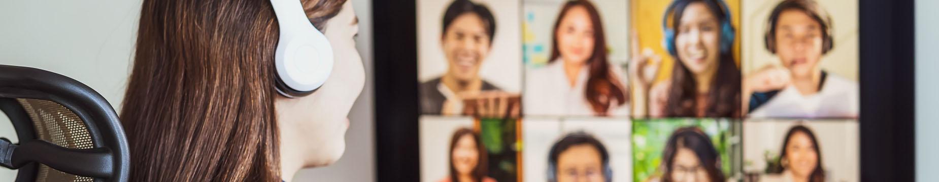 A woman with headphones gazes intently at a computer screen, immersed in her digital experience.