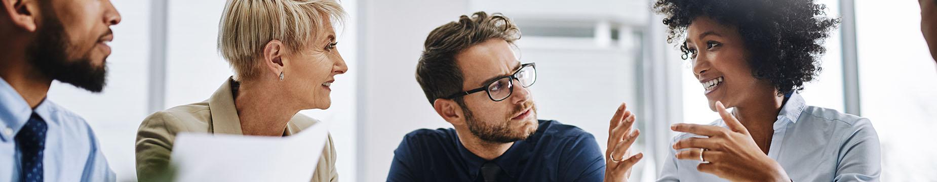 A diverse group of individuals engaged in discussion during a professional meeting, exchanging ideas and insights.