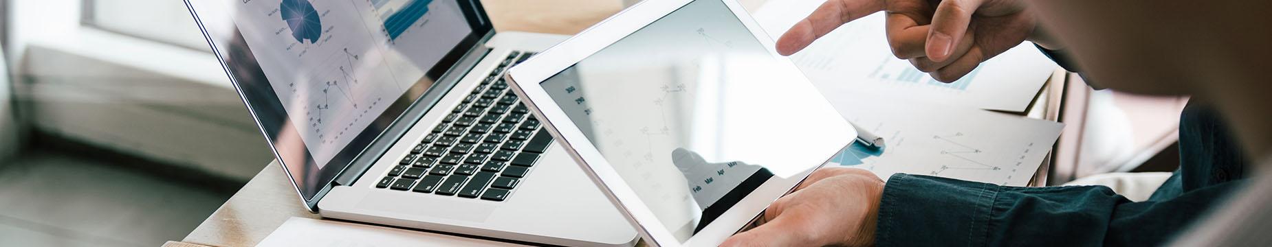 A person focused on a laptop computer, engaged with the screen's content in a well-lit environment.