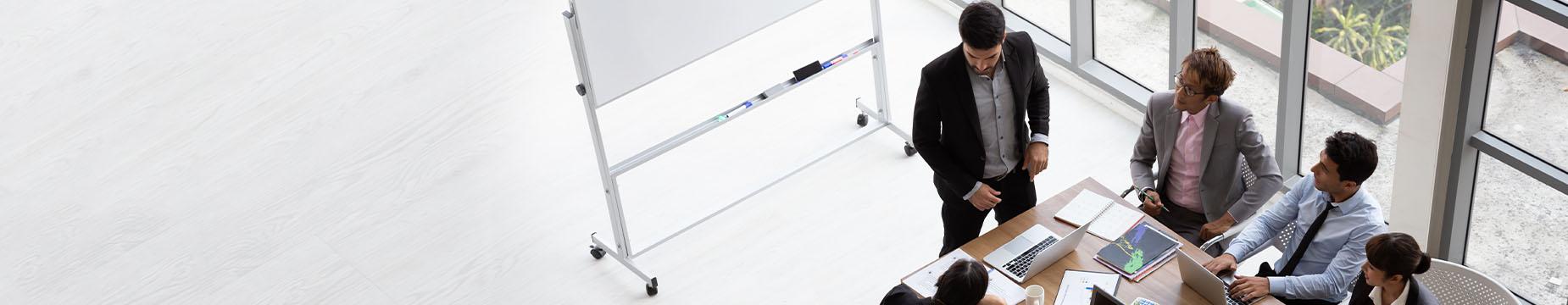 A diverse group of professionals engaged in discussion around a conference table in a modern office setting.