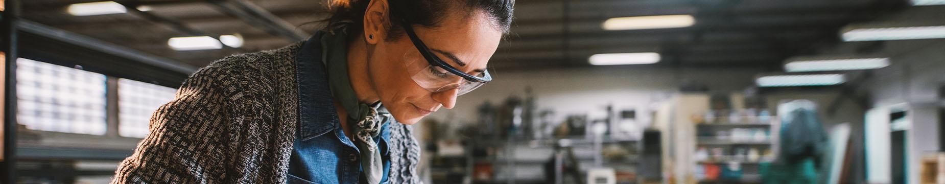 A woman focused on her project, surrounded by tools and materials in a well-organized workshop environment.