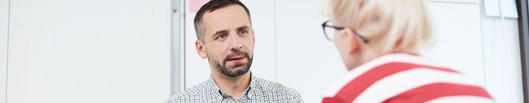 A man and woman engaged in conversation while seated in a professional office setting.