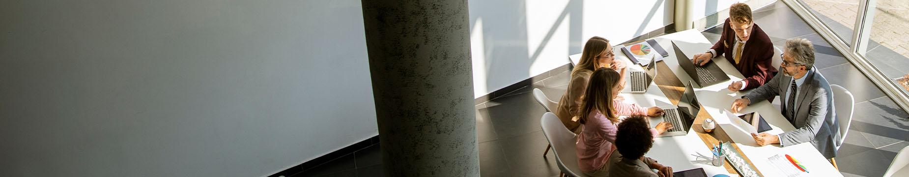 A diverse group of individuals engaged in conversation while seated around a table in a collaborative setting.