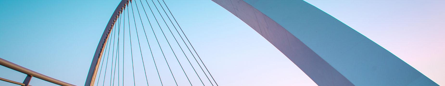 A man cycling across a bridge, showcasing a blend of nature and urban scenery in the background.