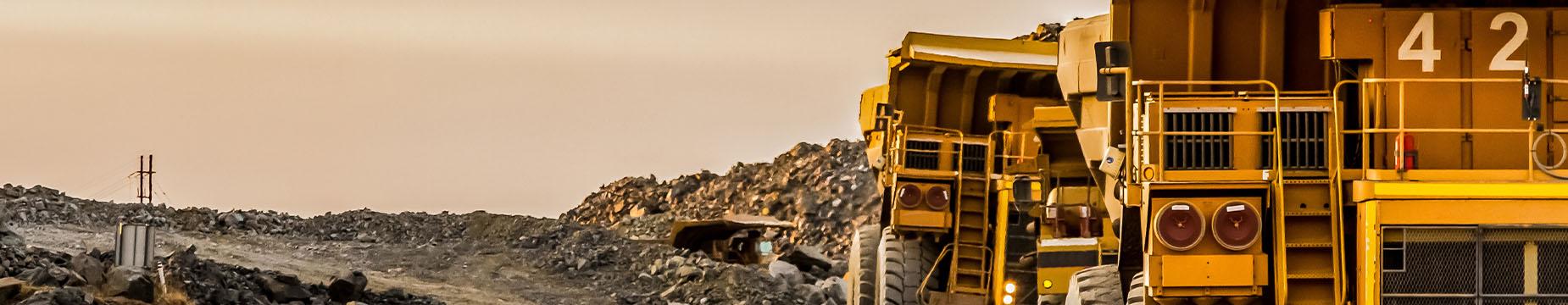 A large dump truck is parked on a dirt road, surrounded by a natural landscape, showcasing its robust design and functionality.