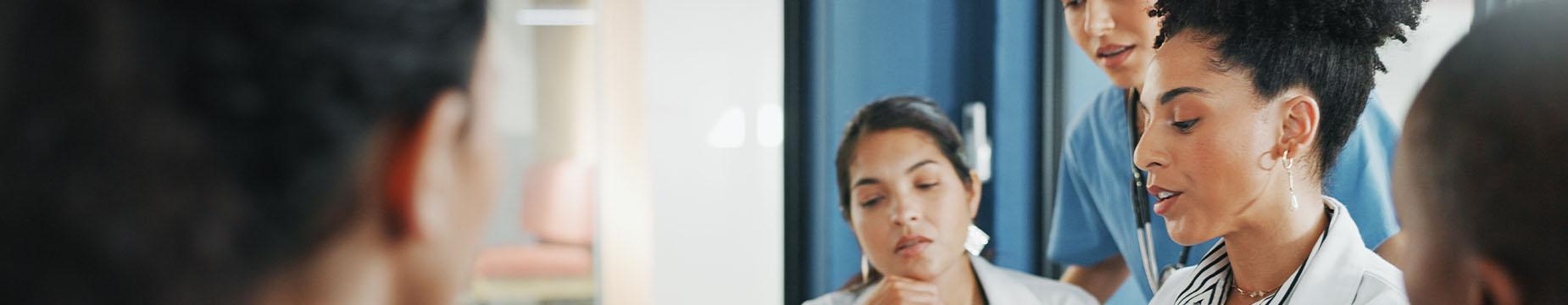 A group of doctors collaboratively examining a tablet, engaged in discussion and analysis of medical information.