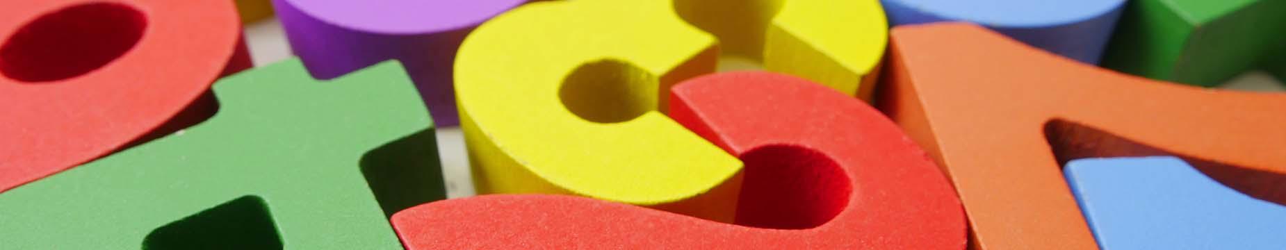 A row of colorful books neatly arranged on a polished wooden table, showcasing their spines and titles.