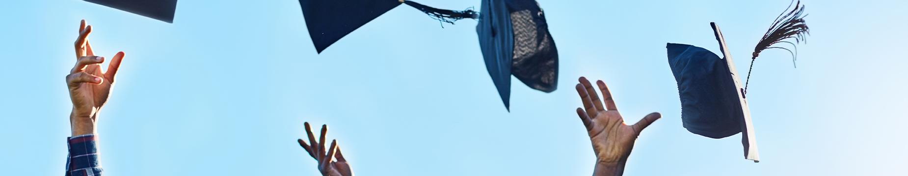 Graduates joyfully tossing their caps into the air, celebrating their academic achievements in a moment of triumph.