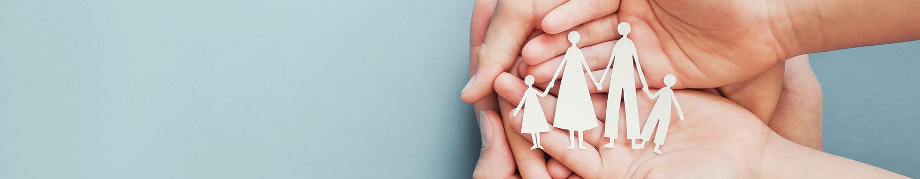 A person's hands hold a paper cutout of a family, symbolizing unity and togetherness in a heartfelt display.