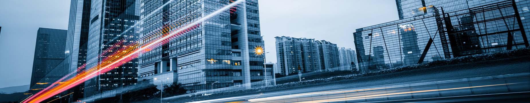 A bustling city street lined with tall buildings and parked cars, showcasing urban life and architecture.
